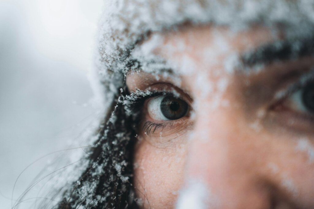 A person's eye and face covered in snow.